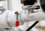 Frozen liquid nitrogen carrying pipes with a valve and black plastic lever close up in a science laboratory 2020