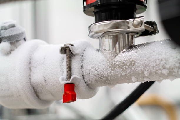 Frozen liquid nitrogen carrying pipes with a valve and black plastic lever close up in a science laboratory 2020